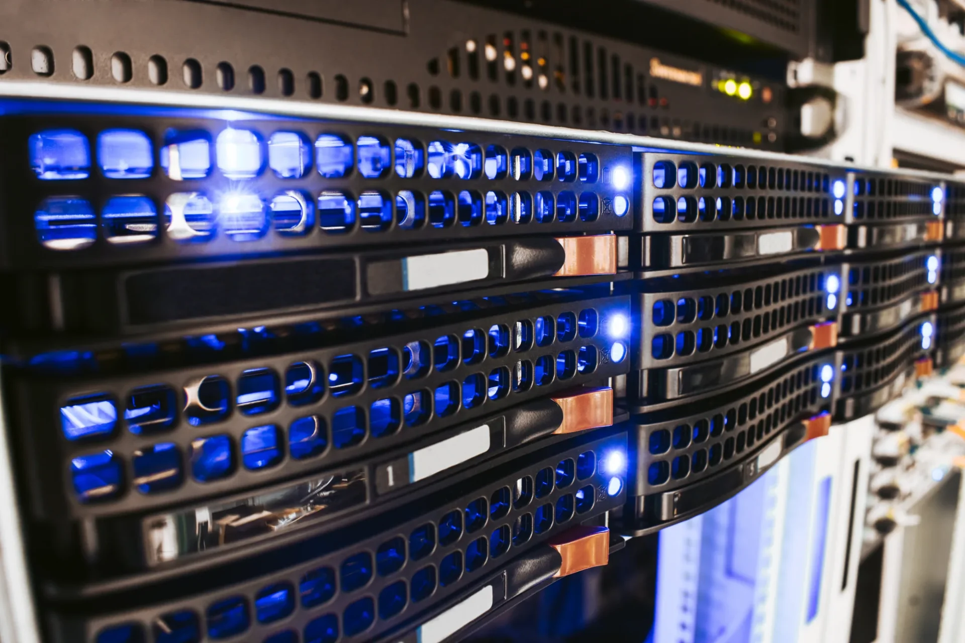 Nahaufnahme von Server-Racks, an deren Frontblenden blaue LEDs leuchten, die eine hochtechnologische, moderne Rechenzentrumsumgebung zeigen.